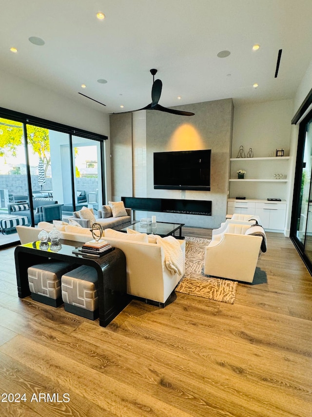 living room featuring ceiling fan, wood-type flooring, and a fireplace