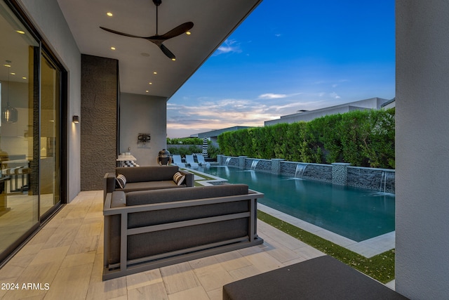 pool at dusk with a patio area, pool water feature, an outdoor hangout area, and ceiling fan