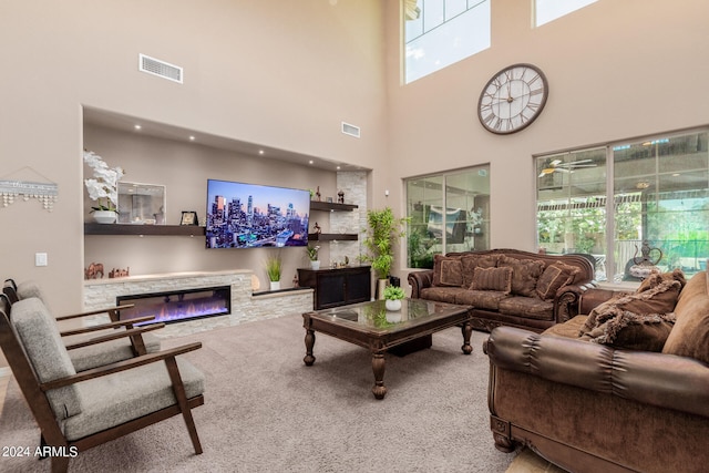 living room with a healthy amount of sunlight, carpet floors, a fireplace, and a high ceiling