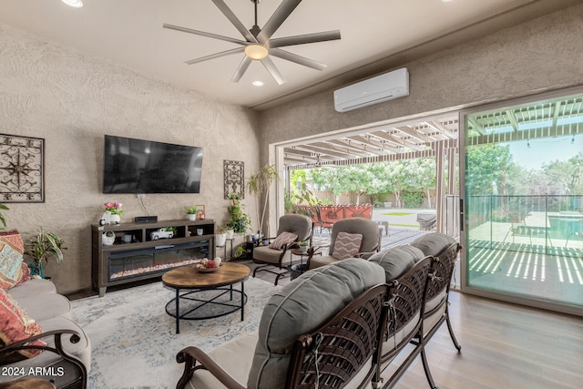 living room with ceiling fan, light hardwood / wood-style floors, a wealth of natural light, and a wall mounted AC