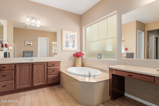 bathroom featuring a wealth of natural light, vanity, hardwood / wood-style flooring, and a bathtub