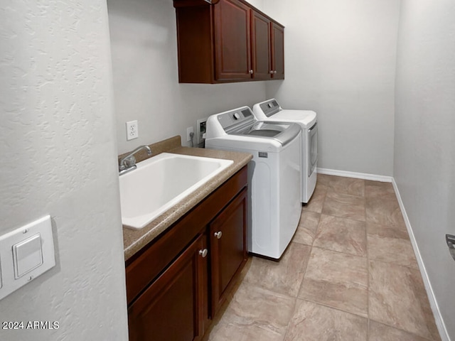 clothes washing area with separate washer and dryer, sink, and cabinets