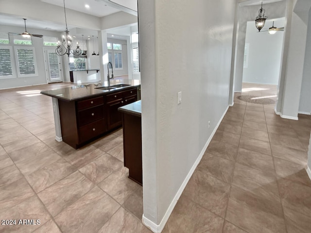 kitchen featuring dark brown cabinetry, sink, decorative light fixtures, and a notable chandelier