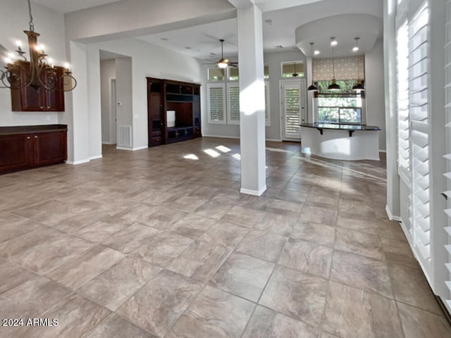 unfurnished living room with ceiling fan with notable chandelier