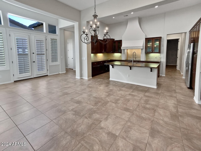 kitchen with premium range hood, a kitchen breakfast bar, decorative light fixtures, a notable chandelier, and stainless steel refrigerator