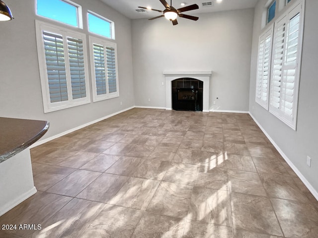 unfurnished living room with ceiling fan and a fireplace