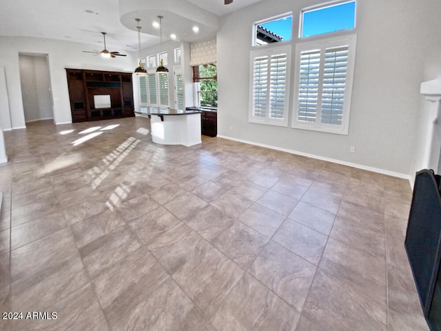 unfurnished living room featuring ceiling fan and light tile patterned floors