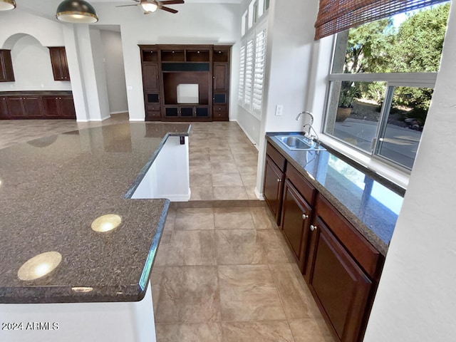 kitchen featuring tasteful backsplash, dark stone counters, ceiling fan, sink, and a kitchen island