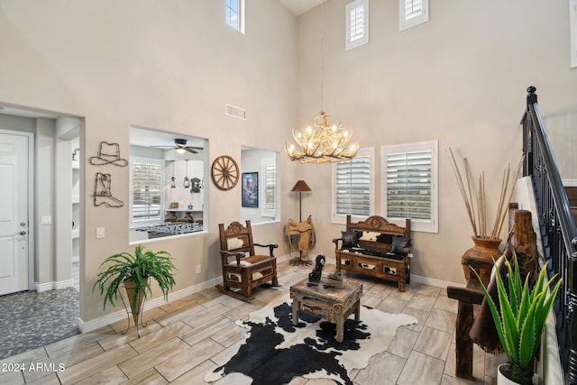 living area featuring ceiling fan with notable chandelier and a high ceiling