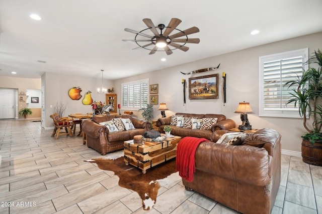 living room featuring ceiling fan with notable chandelier and light wood-type flooring