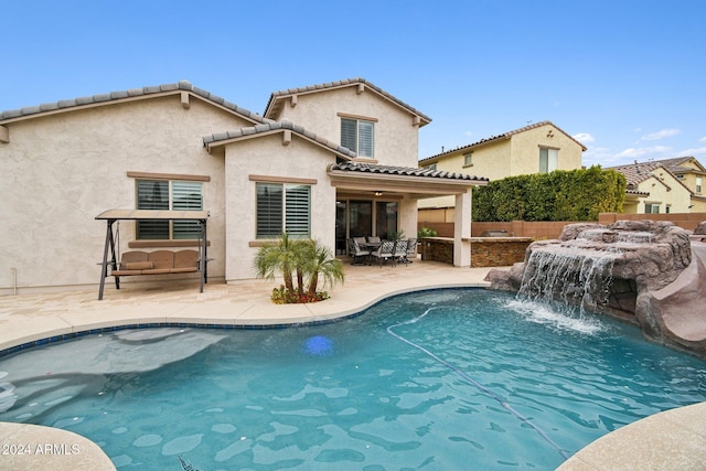 rear view of house featuring a fenced in pool, pool water feature, and a patio