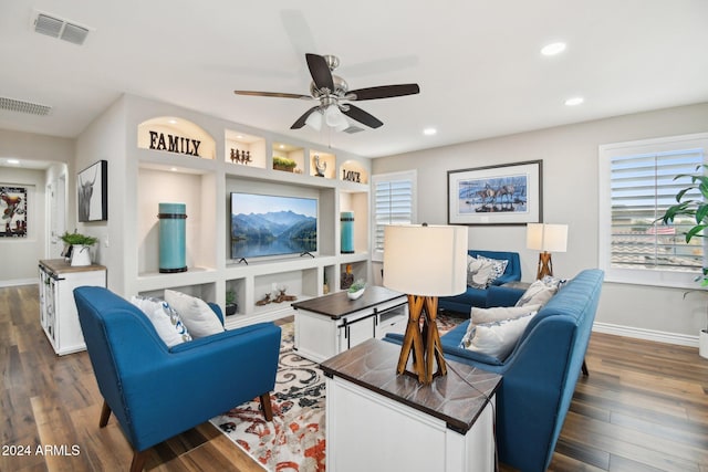 living room with built in shelves, ceiling fan, and dark hardwood / wood-style flooring