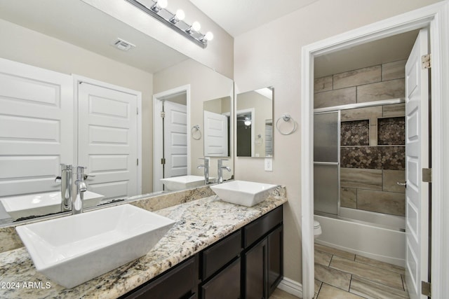 full bathroom featuring vanity, toilet, and bath / shower combo with glass door