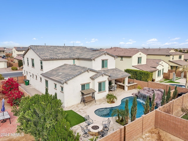 back of property with a fire pit, a patio area, a fenced in pool, and pool water feature