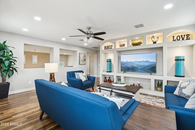 living room with built in shelves, ceiling fan, and hardwood / wood-style floors