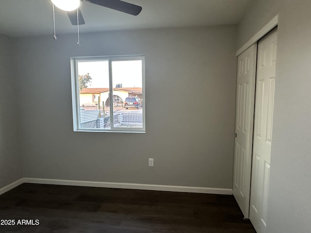 unfurnished bedroom with ceiling fan, dark hardwood / wood-style flooring, and a closet