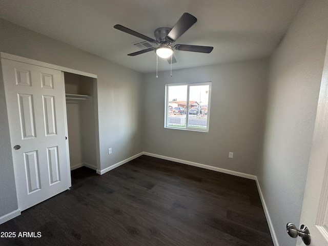 unfurnished bedroom with dark wood-type flooring, ceiling fan, and a closet