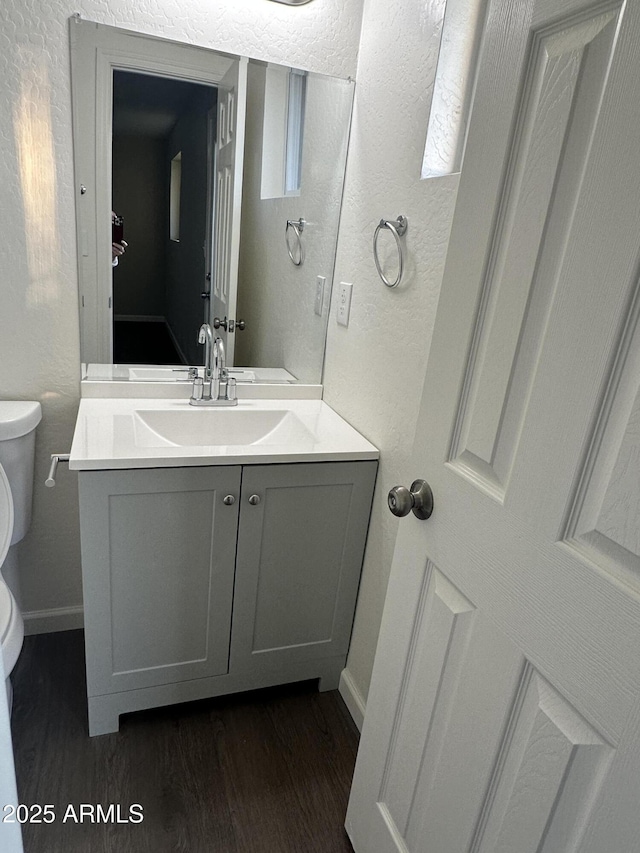 bathroom featuring vanity, hardwood / wood-style flooring, and toilet