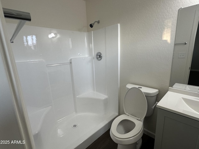 bathroom featuring vanity, toilet, and walk in shower