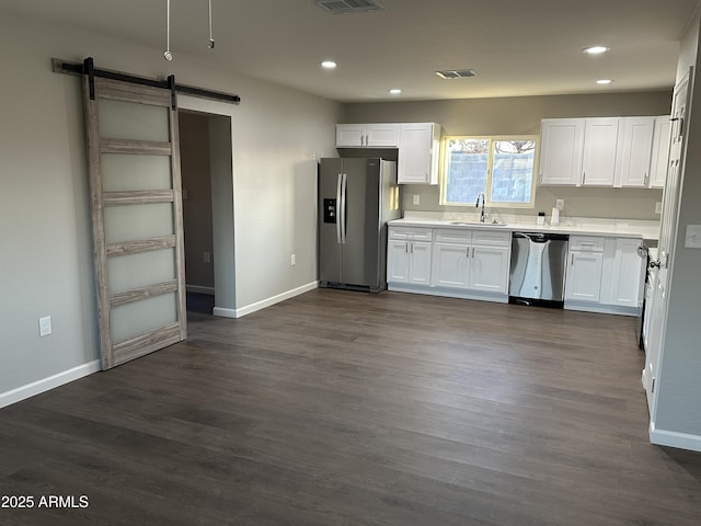 kitchen featuring stainless steel appliances, white cabinetry, a barn door, and sink