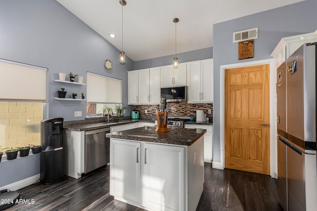 kitchen with appliances with stainless steel finishes, dark wood-type flooring, white cabinetry, and a center island