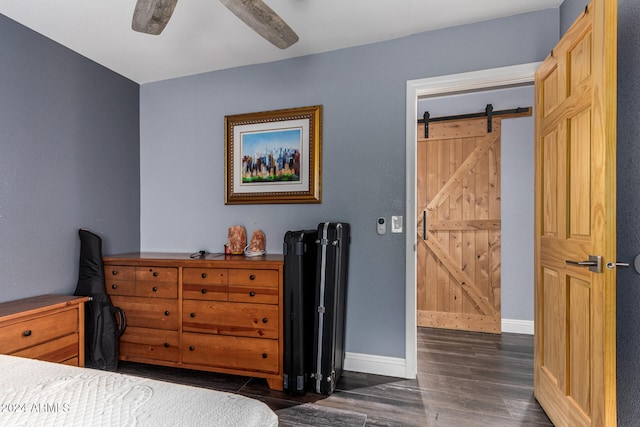 bedroom with a barn door, dark hardwood / wood-style floors, and ceiling fan