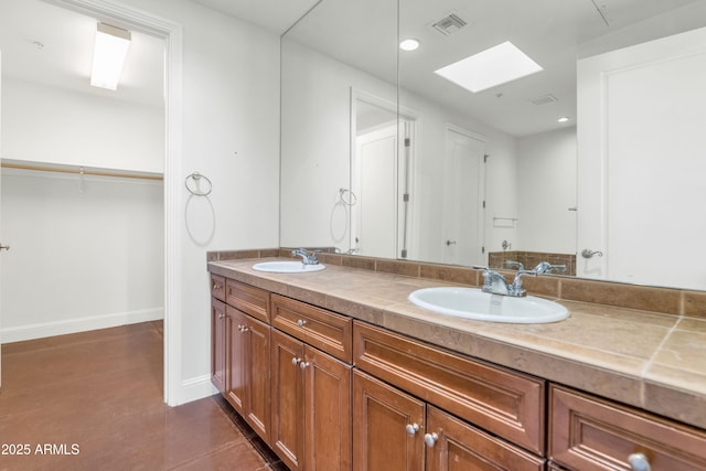 bathroom with tile patterned floors, a skylight, and vanity