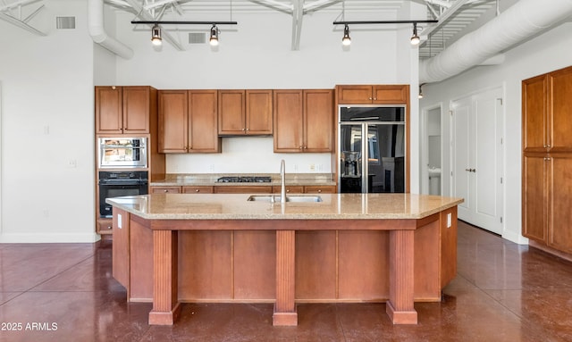 kitchen featuring sink, a center island with sink, black appliances, and a high ceiling