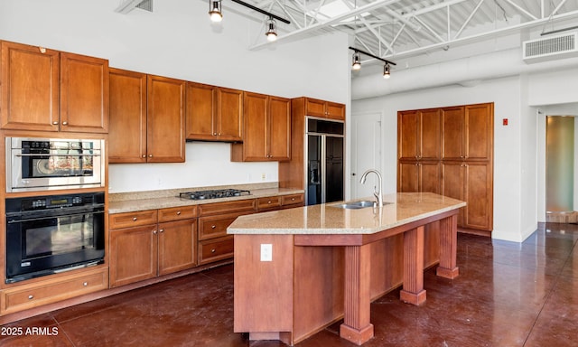 kitchen with sink, a kitchen island with sink, a high ceiling, paneled refrigerator, and stainless steel gas stovetop