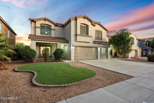 mediterranean / spanish house with a tiled roof, stucco siding, an attached garage, and driveway