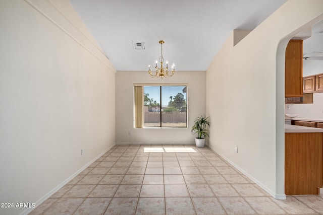 tiled spare room featuring an inviting chandelier