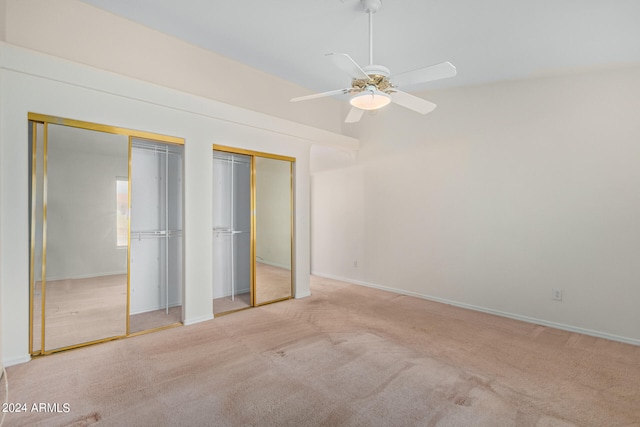 unfurnished bedroom featuring light colored carpet, ceiling fan, and two closets