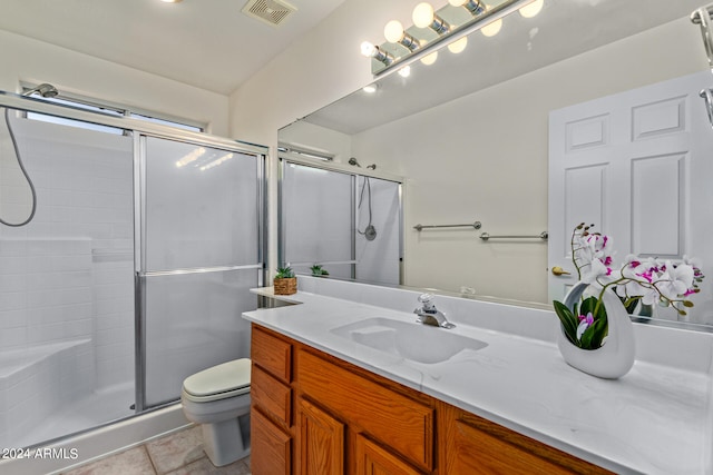 bathroom featuring tile floors, toilet, large vanity, and walk in shower