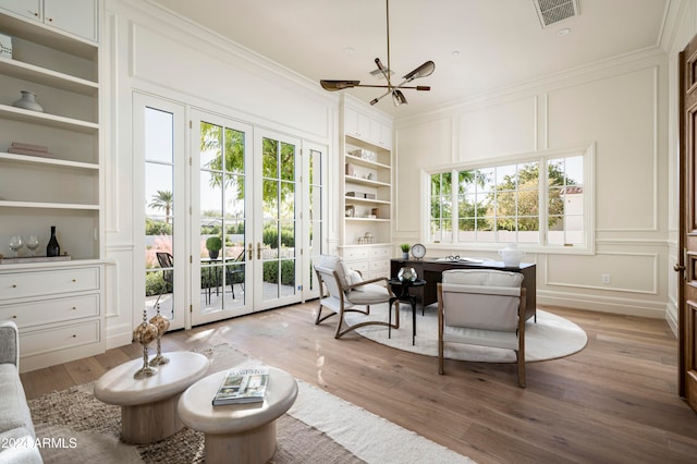 sunroom / solarium featuring plenty of natural light, an inviting chandelier, and french doors