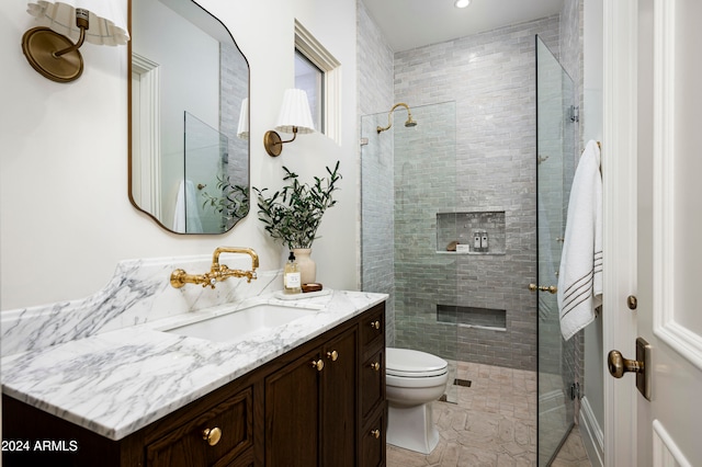 bathroom with vanity, toilet, and tiled shower