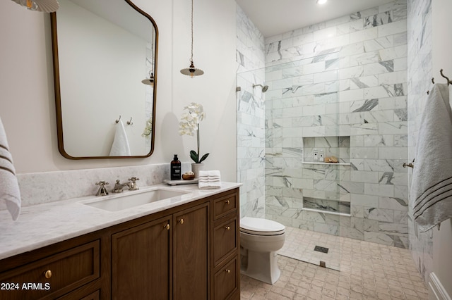 bathroom with a tile shower, vanity, and toilet