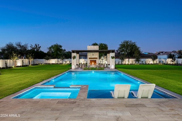 pool at dusk with a patio area, a multi sided fireplace, a yard, and an in ground hot tub