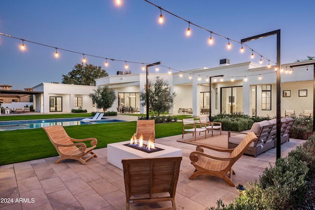 patio terrace at dusk featuring a lawn and an outdoor living space with a fire pit