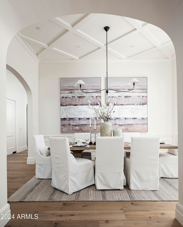 dining area with hardwood / wood-style floors, ornamental molding, and coffered ceiling