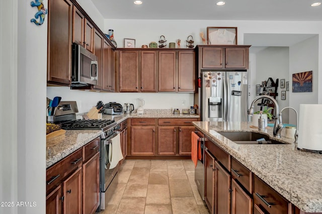 kitchen featuring light stone counters, stainless steel appliances, and sink