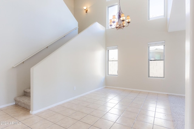 interior space featuring an inviting chandelier, a towering ceiling, light tile patterned floors, and a healthy amount of sunlight