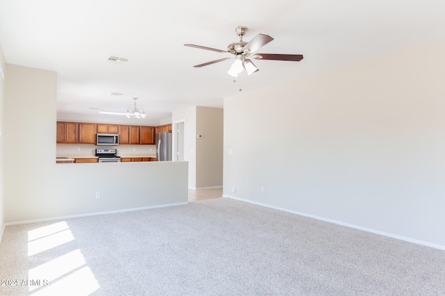 unfurnished living room featuring ceiling fan with notable chandelier and light colored carpet