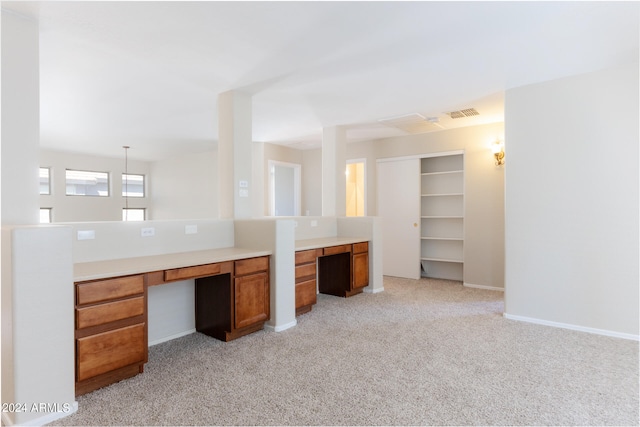 interior space featuring built in desk, light carpet, and decorative light fixtures