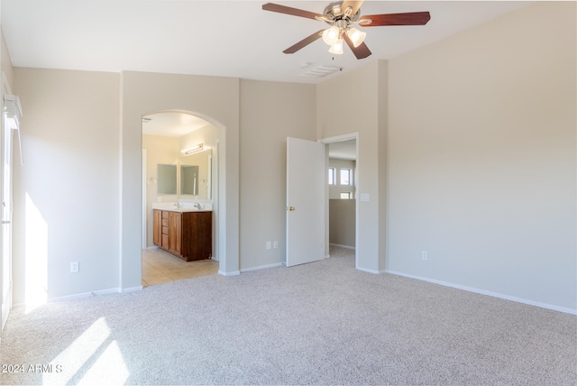 unfurnished bedroom featuring ceiling fan, sink, connected bathroom, and light carpet