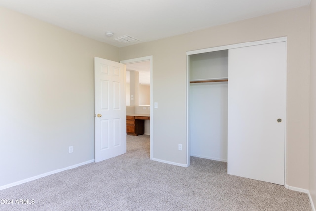 unfurnished bedroom with light carpet and a closet