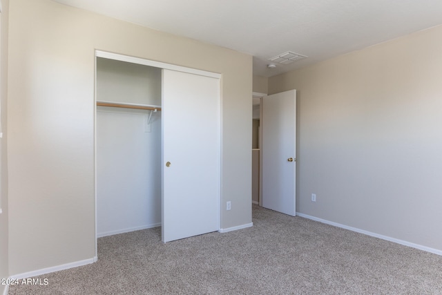 unfurnished bedroom featuring a closet and light colored carpet