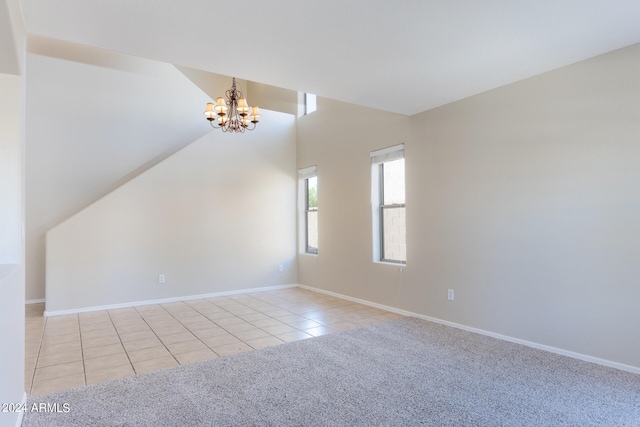 carpeted spare room featuring a notable chandelier and lofted ceiling