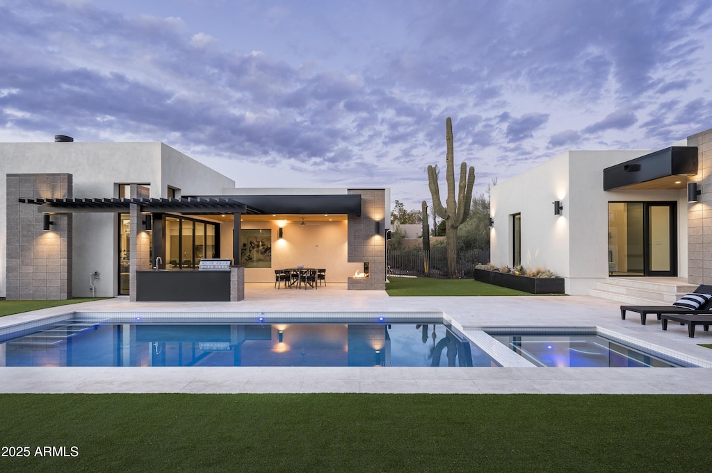 pool at dusk with an in ground hot tub, a pergola, a patio, and a lawn