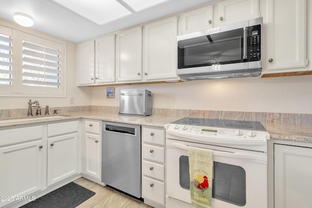 kitchen with appliances with stainless steel finishes, sink, and white cabinets