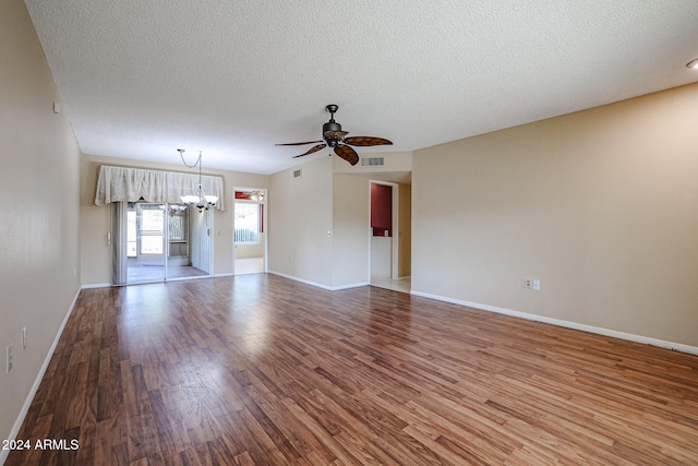 spare room featuring hardwood / wood-style flooring, ceiling fan with notable chandelier, and a textured ceiling